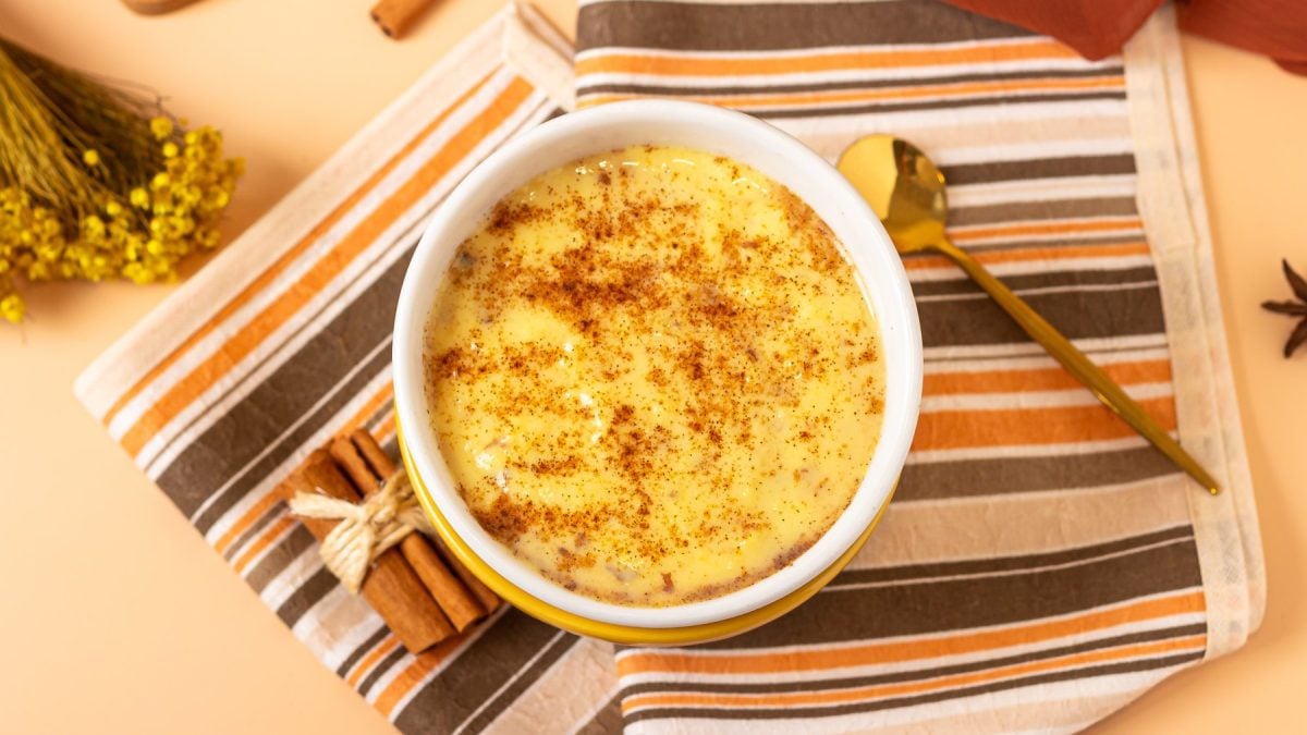Mais-Pudding in einer weißen Schüssel auf einem orange-braun-gestreiften Tuch. Der Hintergrund ist hellorange.