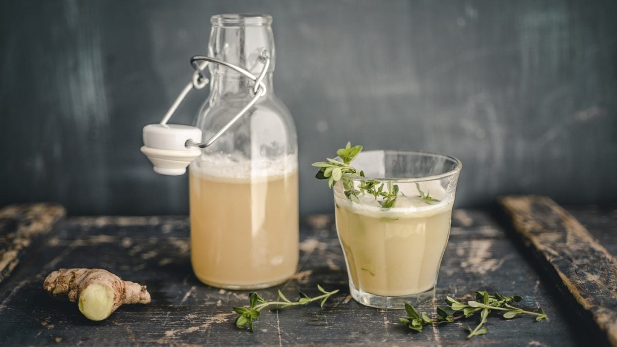 Switchel in einem Glas und einer Flasche vor grauem Hintergrund.