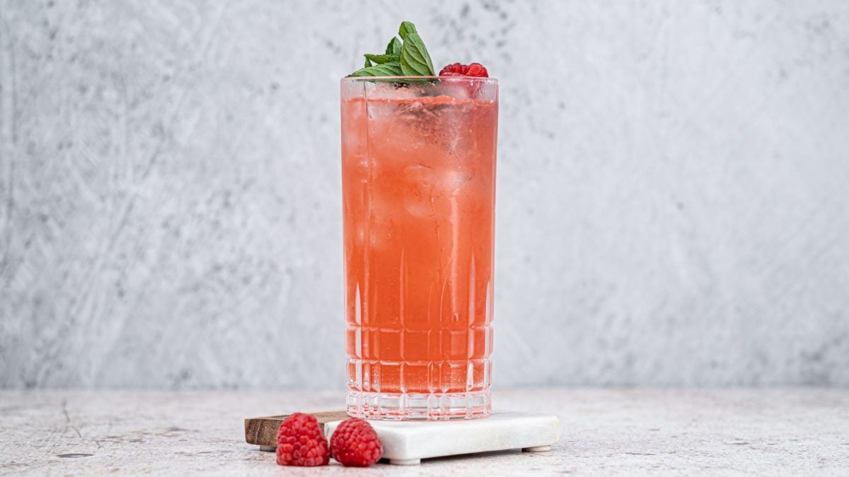 Ein Highball-Glas gefüllt mit Aperol Royal, garniert mit Himbeeren.