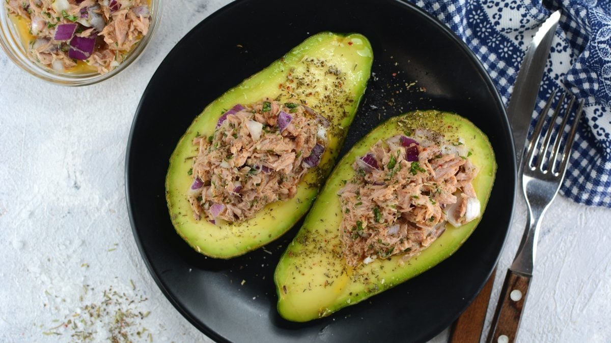 Ein schwarzer Teller mit den Avocados auf einem grauen Tisch. Alles direkt von oben fotografiert.