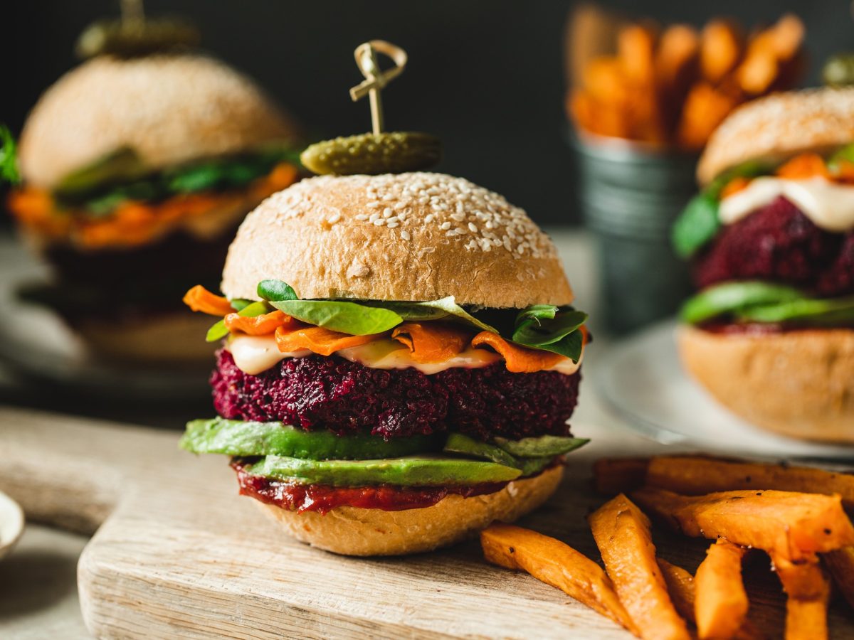 Verschiedene Burger auf einem Holzbrett von der Seite fotografiert.