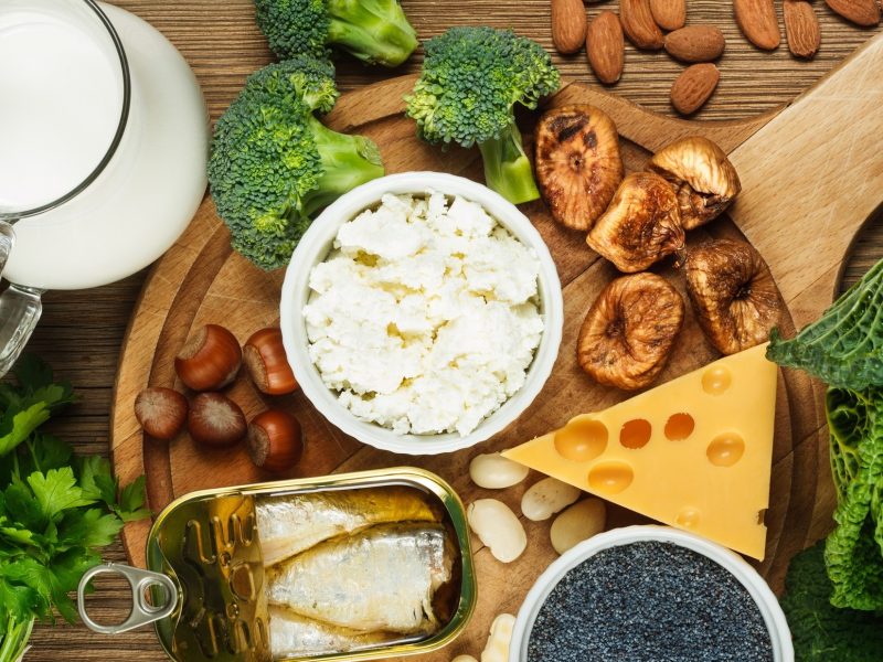 Draufsicht: Ein Untergrund aus Holz, auf dem Lebensmittel mit viel Kalzium, beziehungsweise Calcium, liegen.