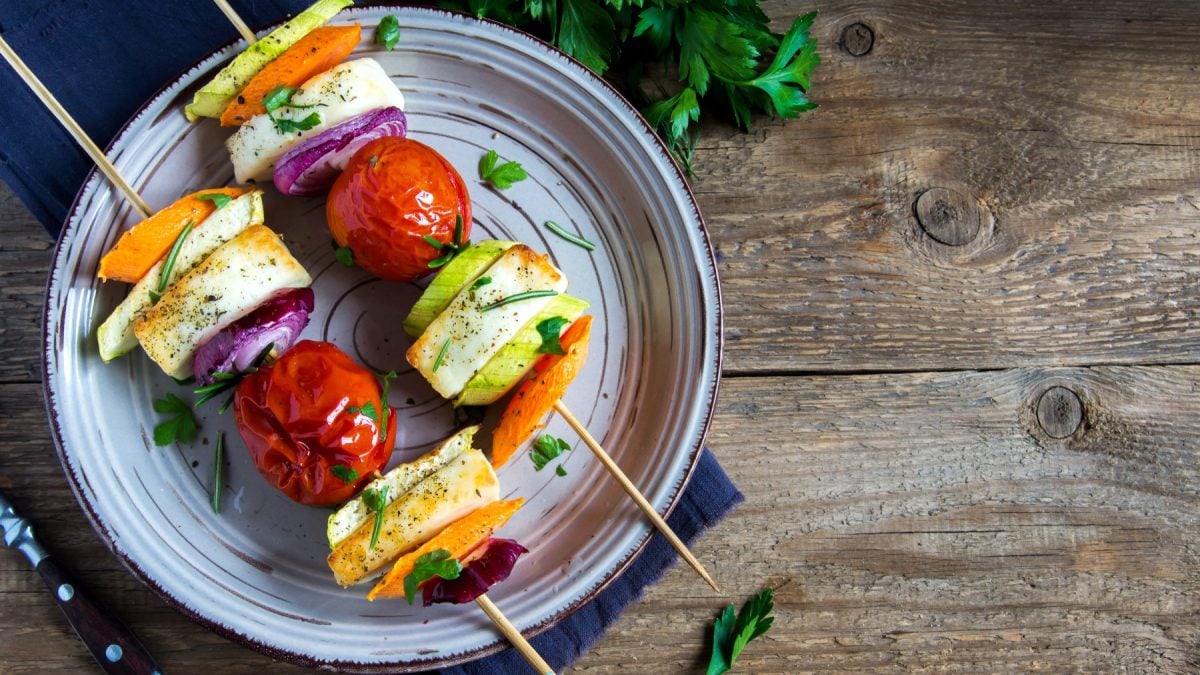 Halloumi-Grillspieße auf einem blauen Teller auf hölzernem Hintergrund.