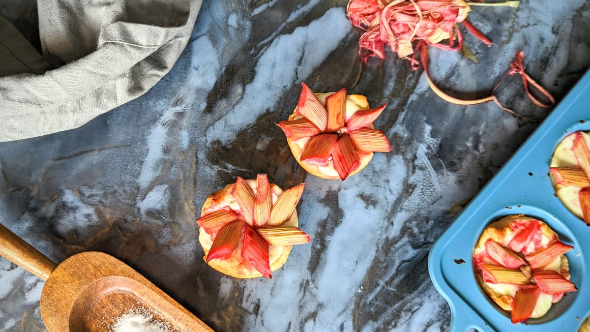 Einige Stücke des kleinen Gebäcks auf einem schwarzen Marmortisch. Daneben Schalen, ein graues Tuch und die Backform mit weiterem Gebäck. Alles direkt von oben fotografiert.