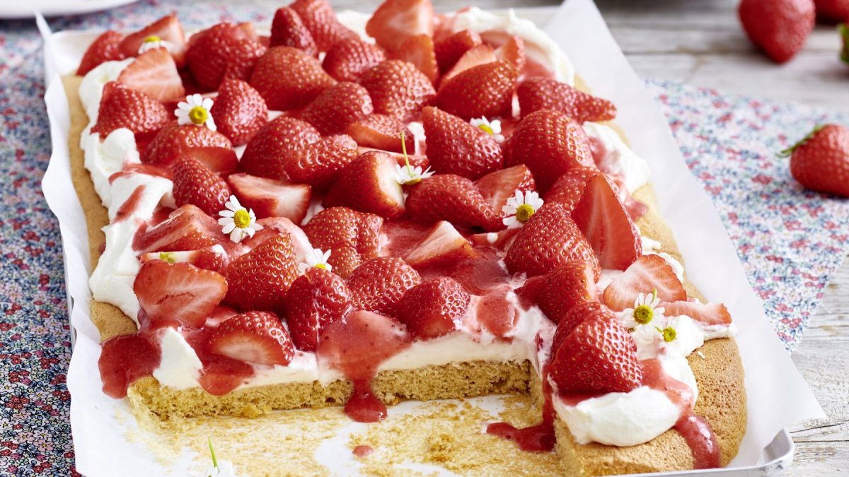 Schneller Erdbeerkuchen: Angeschnitten auf einem Backpapier mit hellem Untergrund.