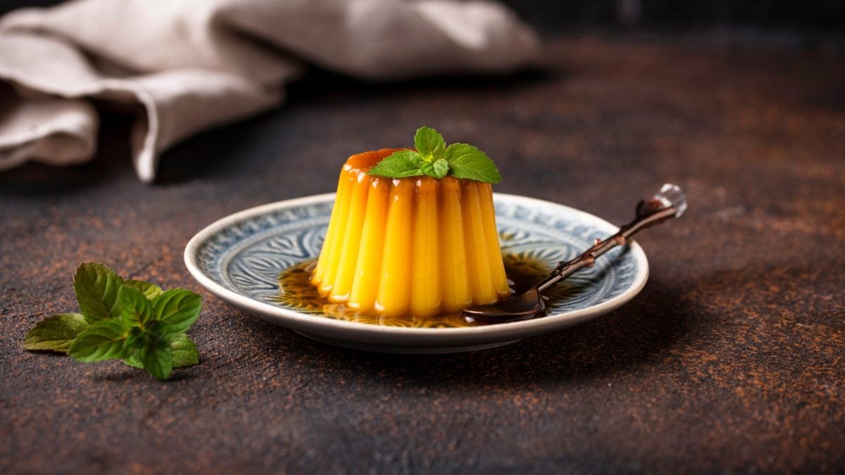 Veganer Flan auf einem weiß/blauen Teller auf braunen Hintergrund.