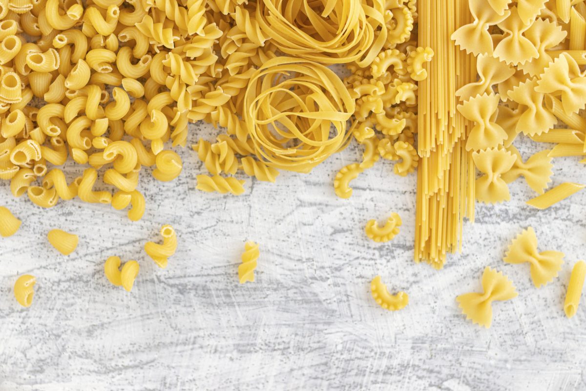 Verschiedene Pastasorten auf weißem Hintergrund von oben fotografiert.