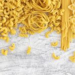 Verschiedene Pastasorten auf weißem Hintergrund von oben fotografiert.
