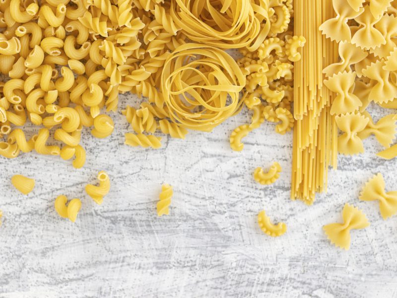 Verschiedene Pastasorten auf weißem Hintergrund von oben fotografiert.