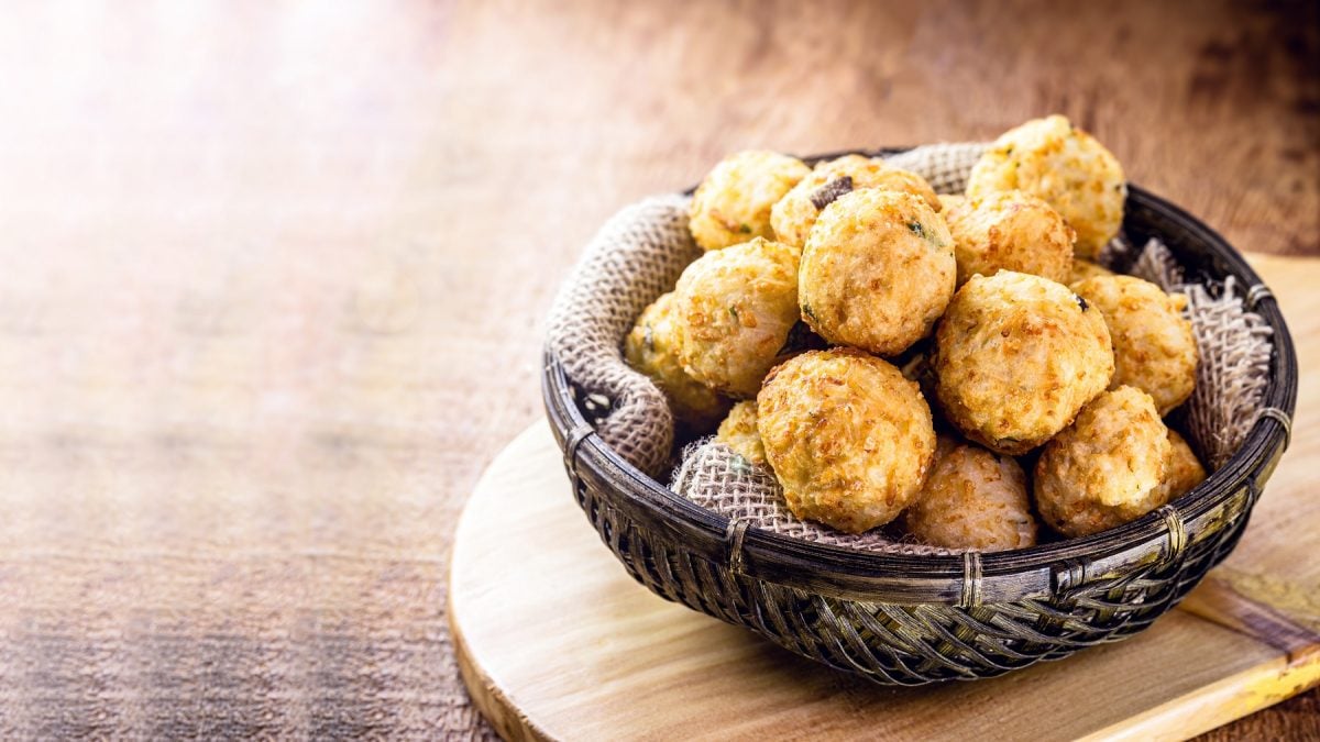 Bolinhos de arroz in einer dunklen Schüssel vor einem hellen, ausgeleuchteten Hintergrund.