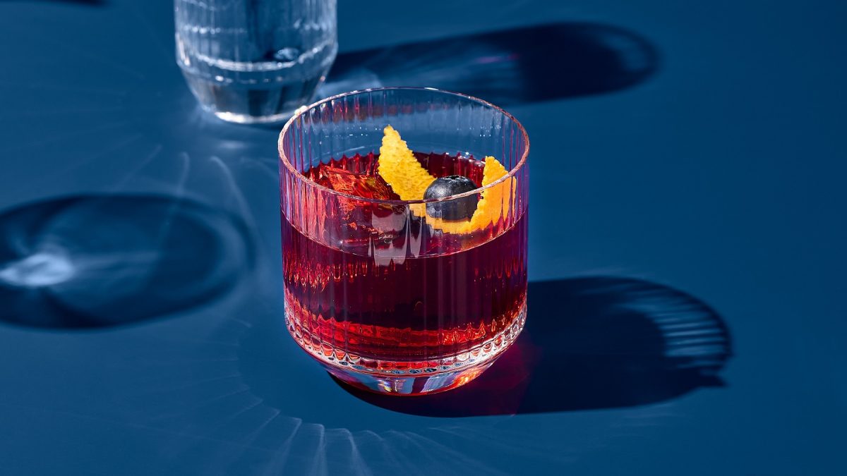 Ein Glas mit dem Campari Amalfi auf blauem Untergrund direkt in der Sonne fotografiert.
