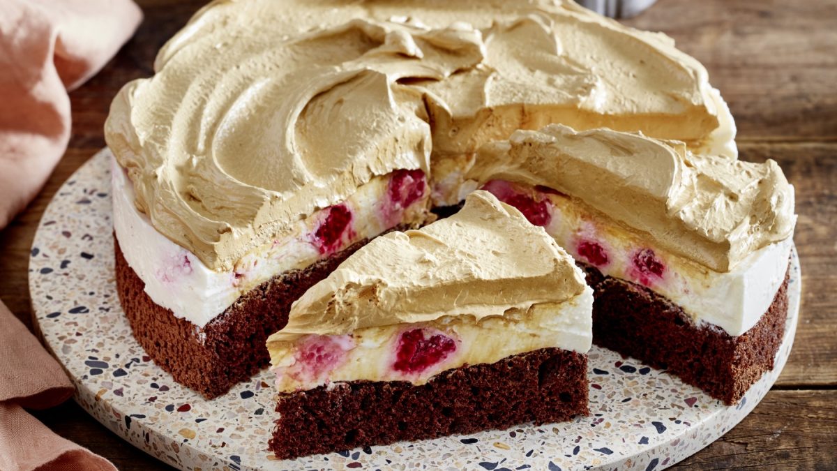 Dalgona-Himbeer-Cheesecake auf einem weißen Teller auf hölzernem Hintergrund.