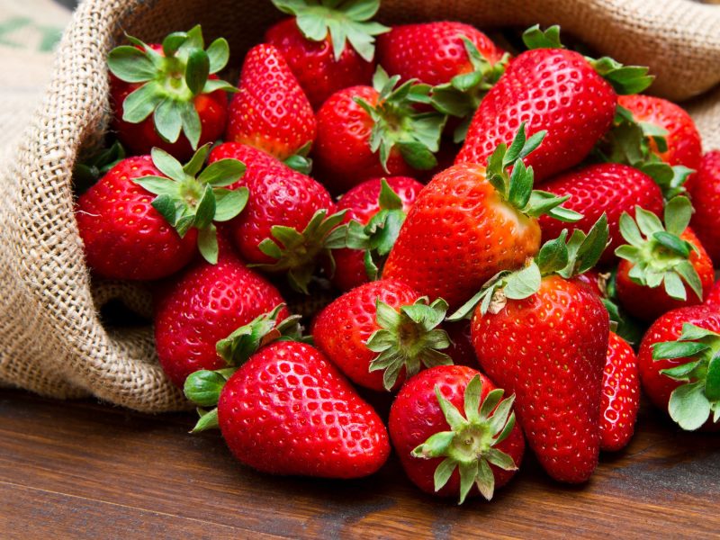 Frontal: Frische Erdbeeren in einem offenen Sack aus Jute