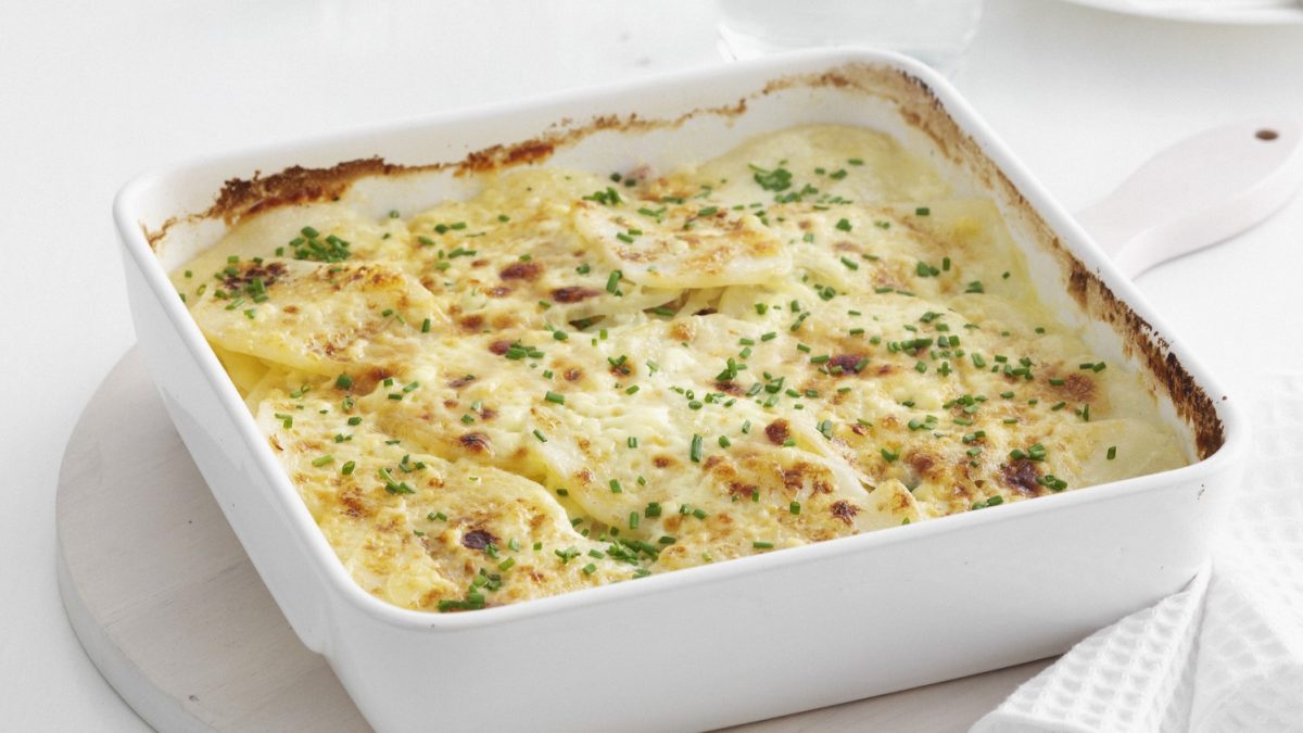 griechischer Kartoffelauflauf in weißer Auflaufform bestreut mit Kräutern.