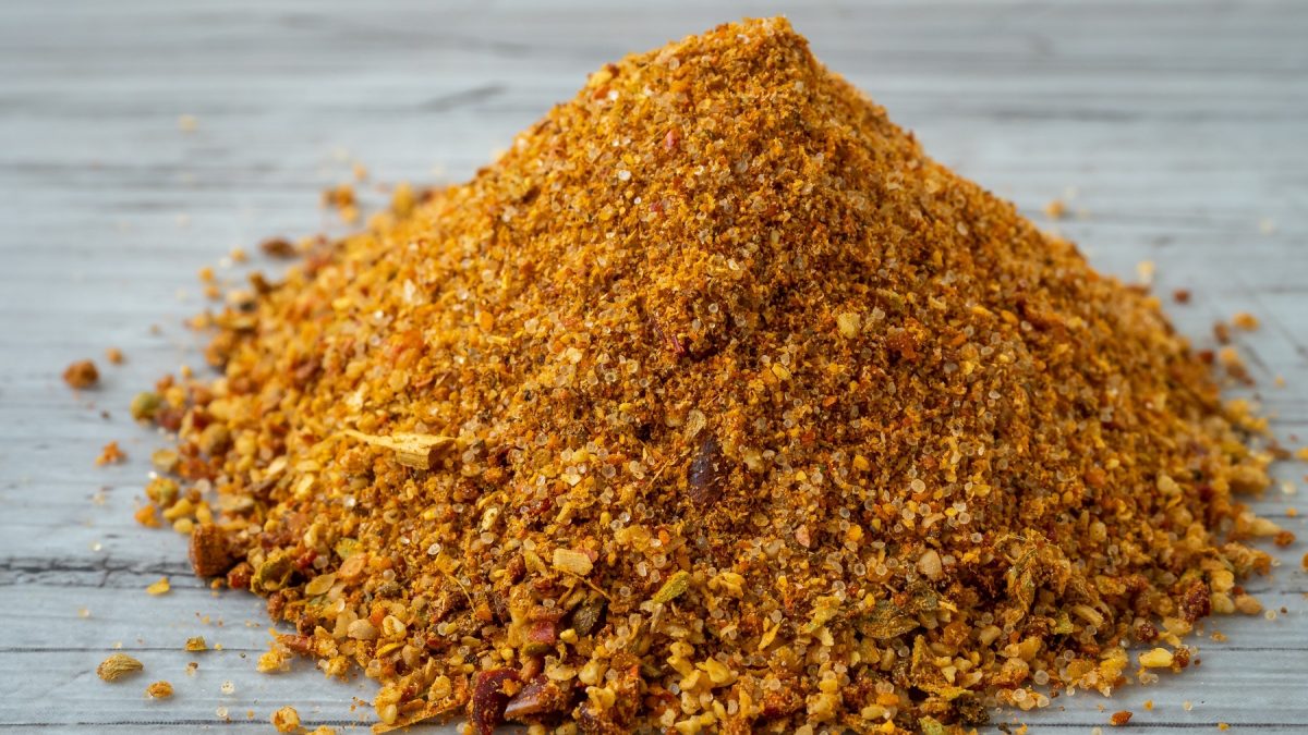 Ein Häufchen mit dem Gewürz auf einem grauen Holztisch. Alles von der Seite und recht nahe fotografiert.