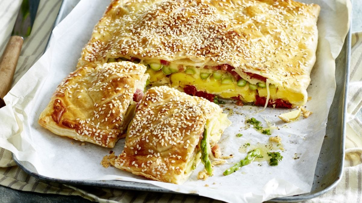 Angeschnittene Käse-Tomaten-Tarte auf weißem Teller.