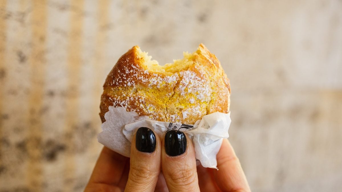 Sfogliatella frolla, die von zwei Händen hochgehalten wird.