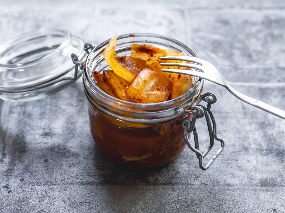 Ein Glas Kimchi auf einem grauen Tisch von schräg oben fotografiert.