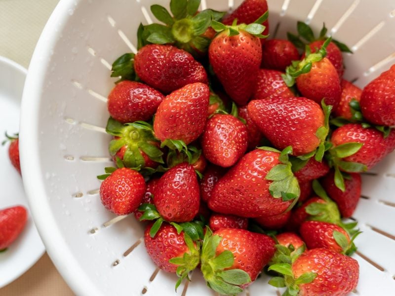 Erdbeeren waschen in einem Plastiksieb / Draufblick