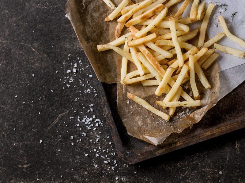 TK-Pommes auf Blech, positioniert auf dunklem Untergrund
