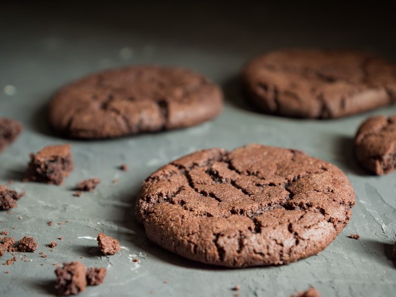 Mehrere Brownie Cookies auf einem grauen Tisch von der Seite fotografiert.