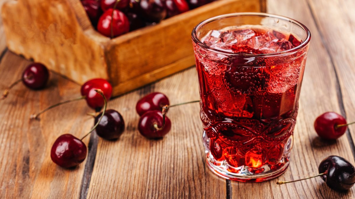 Sleepy Girl Mocktail in einem dekorativen Glas, daneben frische Sauerkirschen.