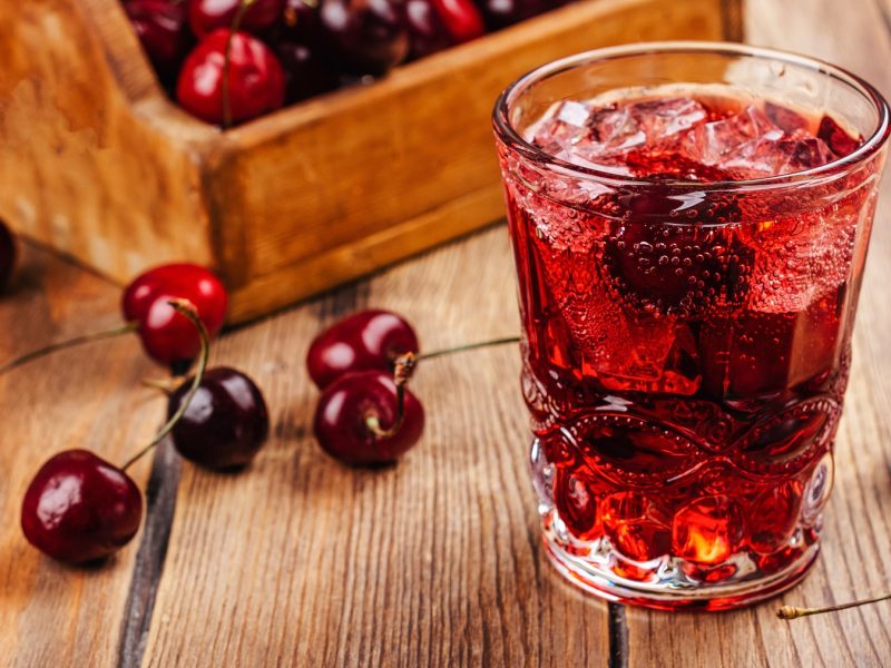 Sleepy Girl Mocktail in einem dekorativen Glas, daneben frische Sauerkirschen.