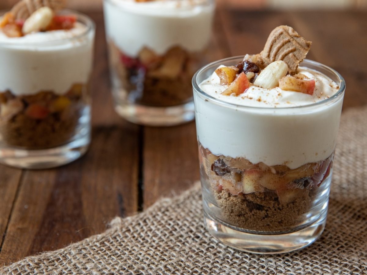 Veganes Bratapfel-Dessert in 3 Gläsern auf hölzernem Hintergrund.