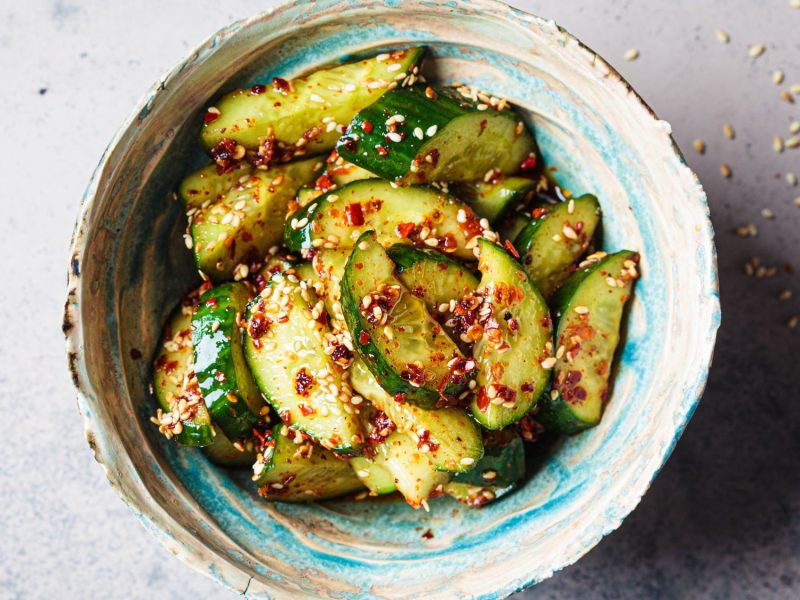 Eine kunstvoll verzierte Schale gefüllt mit einem japanischen Gurkensalat mit Sesam und Chili.