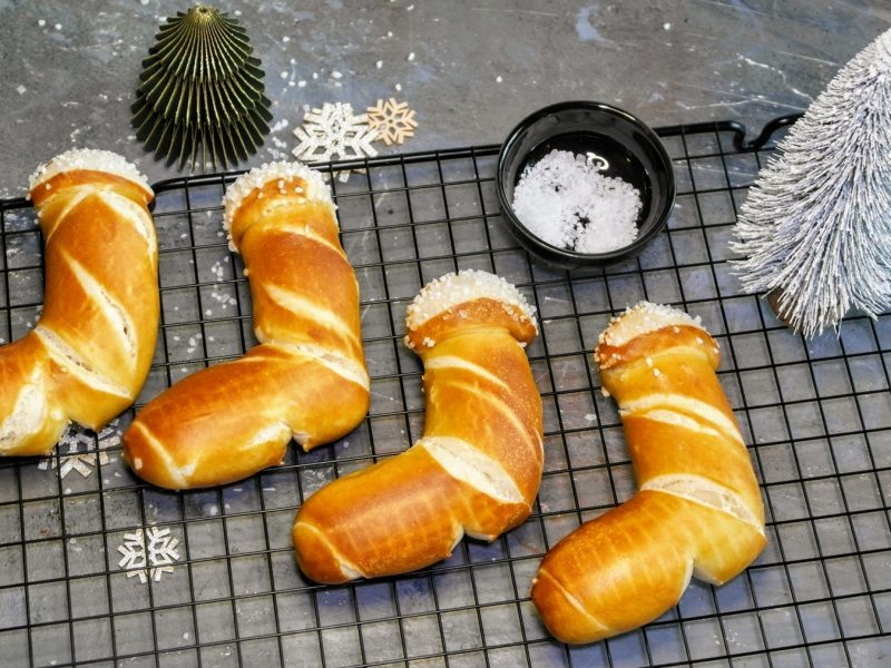 Die Laugen-Stiefel auf einem schwarzen Backgitter und grauem Steintisch mit weihnachtlicher Dekoration von schräg oben fotografiert.