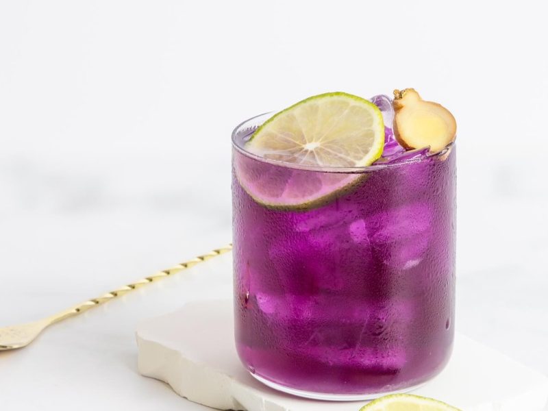 Frontalansicht auf ein Glas mit einem violetten Lavender Mule, daneben ein Barlöffel.