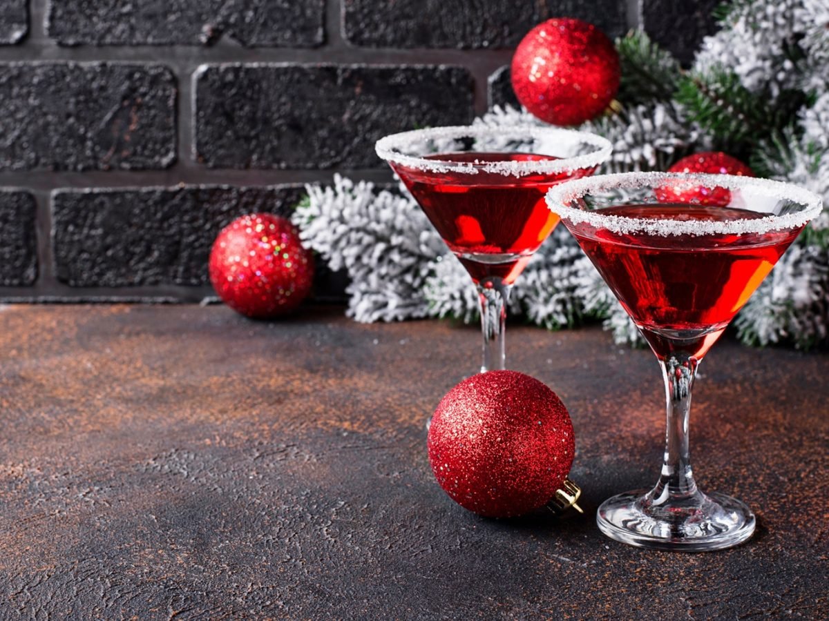 Zwei Martinigläser mit red Martini vor weihnachtlicher Dekoration.