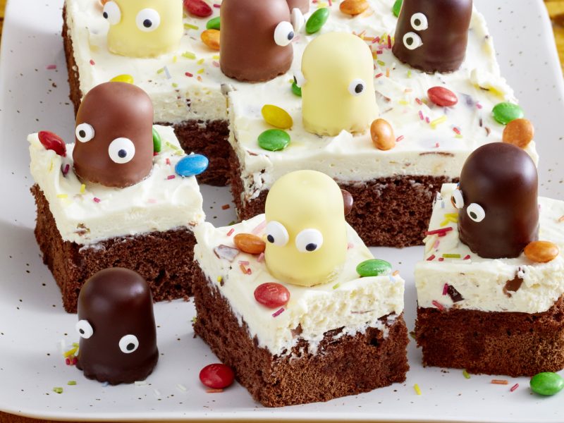 Viereckige Schokokuss-Quark-Schnitten, die Schokoküsse mit Zuckeraugen als Deko auf jedem Stück haben.
