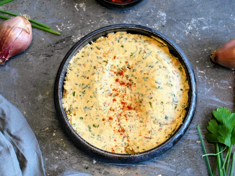 Eine graue Schale mit der Cowboy Butter auf einem grauen Steintisch, mit Kräutern und Schalotten direkt von oben fotografiert.