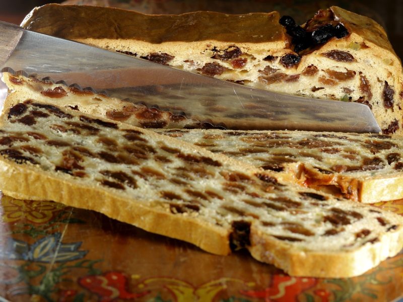 Draufsicht, leicht schräg: Ein angeschnittener Bremer Klaben liegt auf einem Holzbrett.