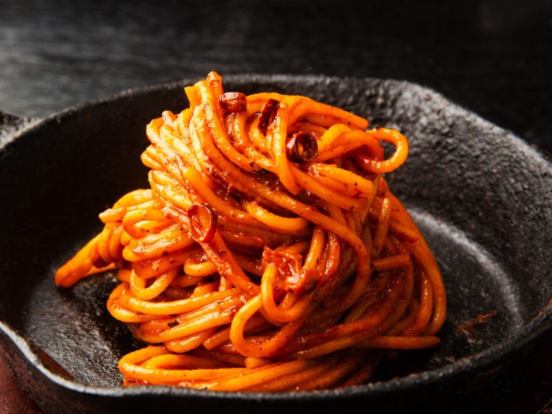Frontal, schräg von oben: Eine schwarze gusseiseren Pfanne mit Spaghetti all'Assassina.