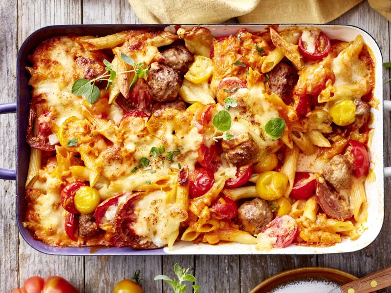 Draufsicht: Hackbällchen-Auflauf in Auflaufform auf Holzuntergrund.