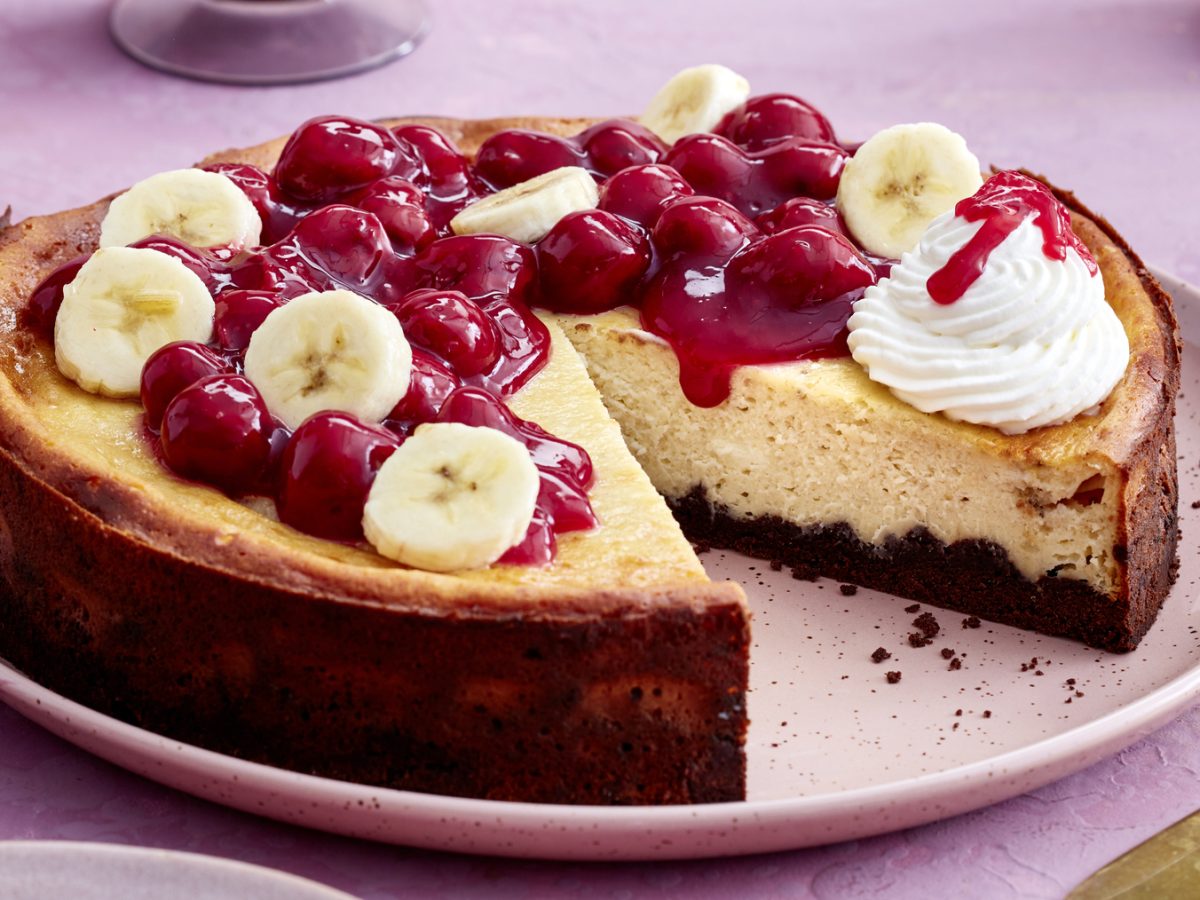 Angeschnittener KiBa-Cheesecake auf rundem Teller mit rosa Hintergrund.