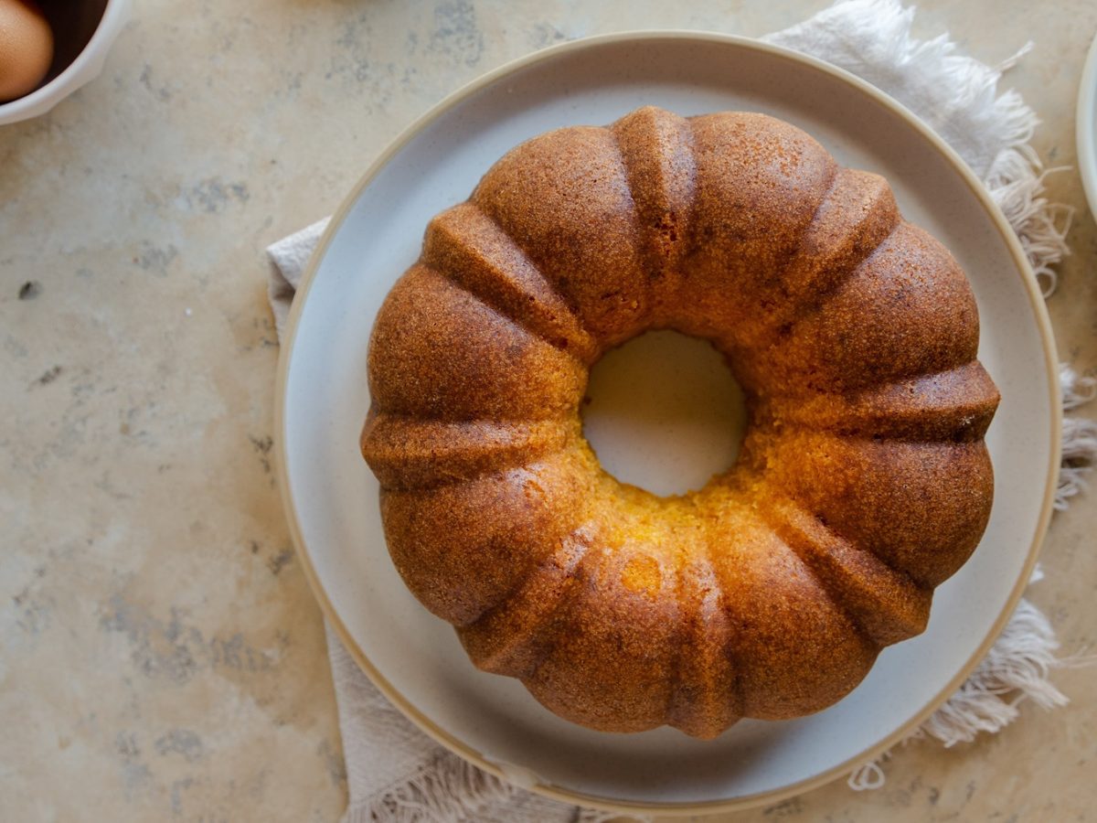 Der Rührkuchen von oben auf einem hellen Teller mit beigem Untergrund fotografiert.