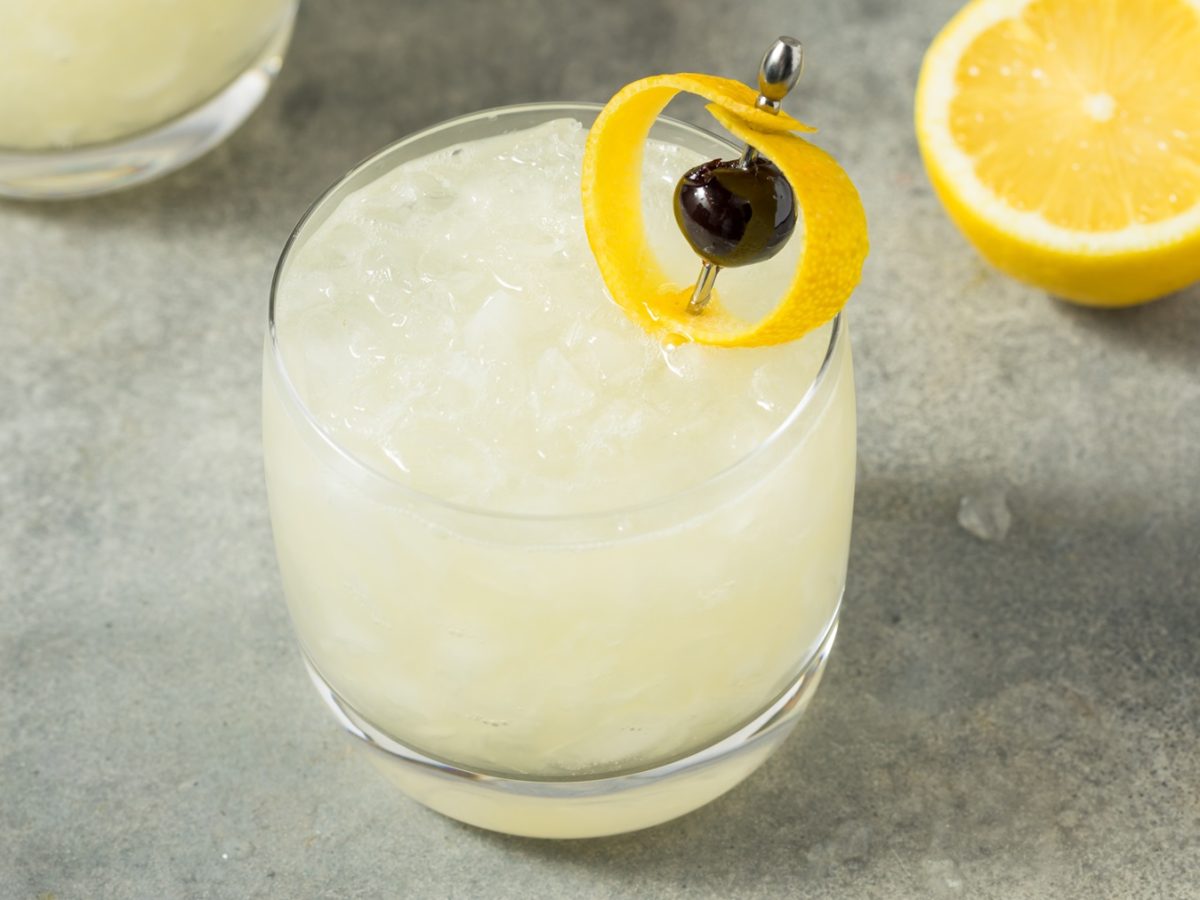 Draufsicht auf ein Glas mit dem Saturn-Cocktail, der mit einer Zitronenschale und einer Amarenakirsche garniert wurde.