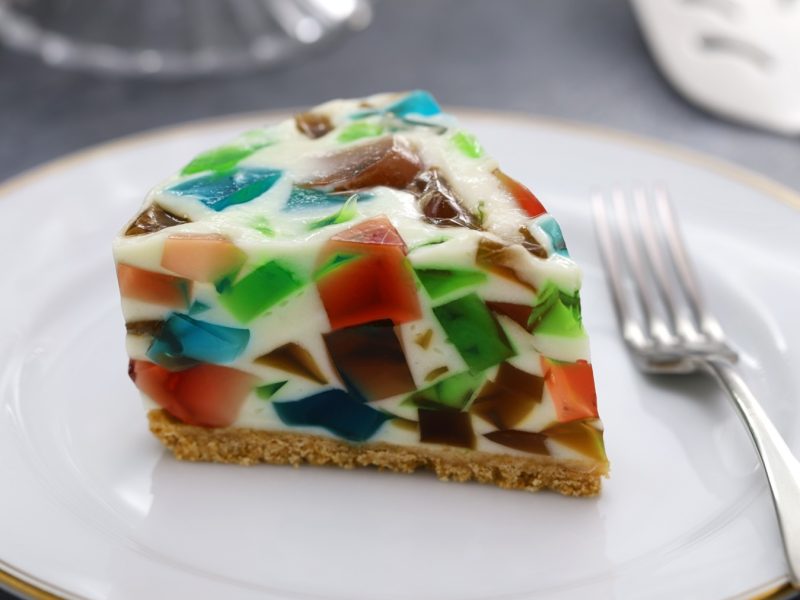 Ein Stück Terrazzo Kuchen auf einem weißen Teller mit goldenem Rand. Alles auf einem grauen Tisch mit silberner Gabel.