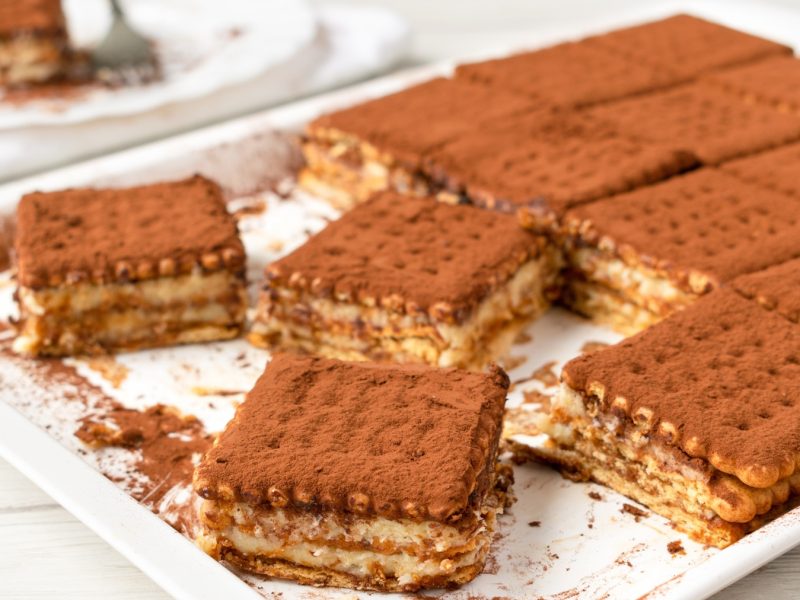 Der Brick Cake auf einem weißen Tablett und hellem Holztisch. Alles von der Seite fotografiert.