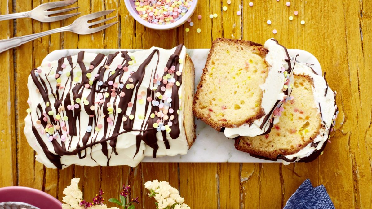 Funfetti-Kuchen mit Schwips auf einem weißen Teller auf hölzernem Hintergrund.