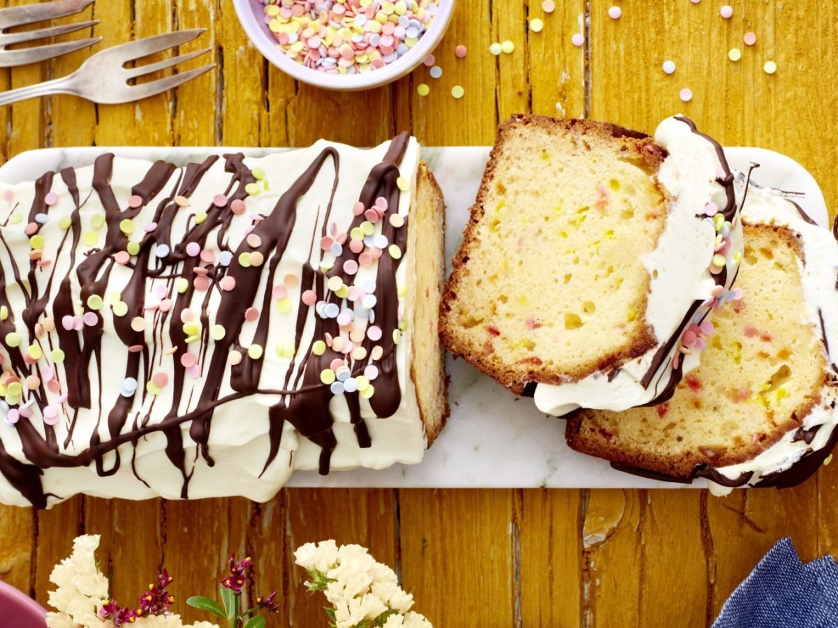Funfetti-Kuchen mit Schwips auf einem weißen Teller auf hölzernem Hintergrund.