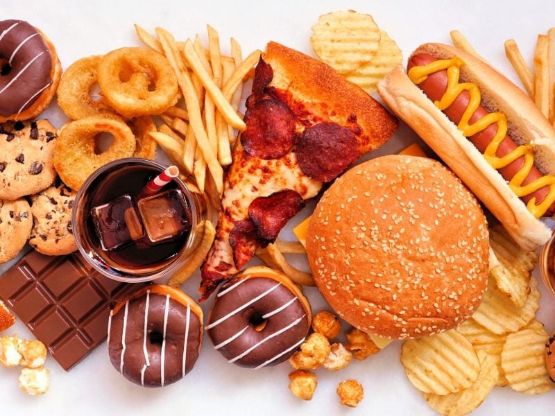 Vogelperspektive: viele verschiedene hochverarbeitete Fastfood-Gericht und zuckerhaltige Getränke.