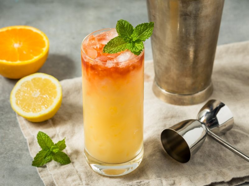 Ein tropischer Fog Cutter mit Orangensaft, Sherry und Crushed Ice, garniert mit frischer Minze, steht auf einer Leinenserviette.