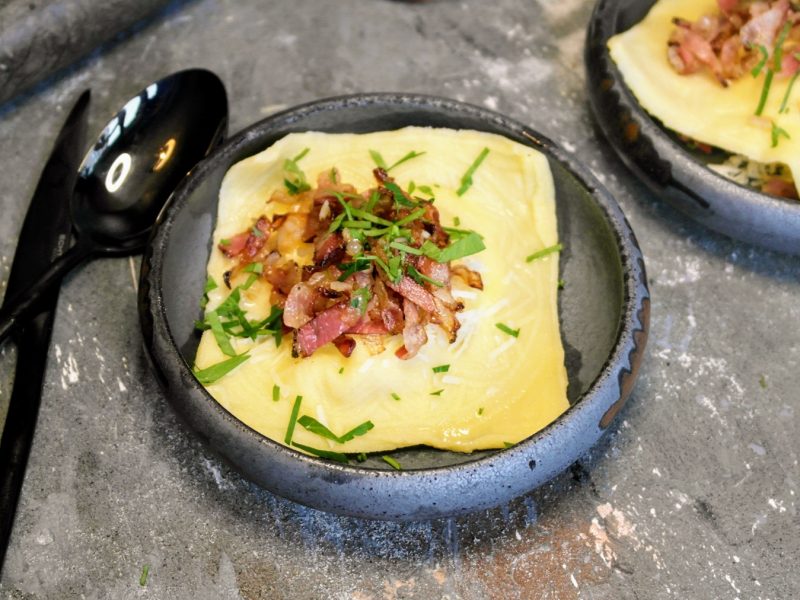 Zwei graue Schälchen mit den Ravioli auf einem Steintisch von schräg oben fotografiert.