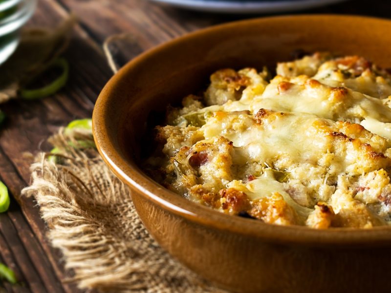 Draufsicht, schräg: Ein überbackener Spitzkohl in einer runden Schüssel aus Ton. Der Kohl ist mit einer dicken Schicht aus Käse überzogen.