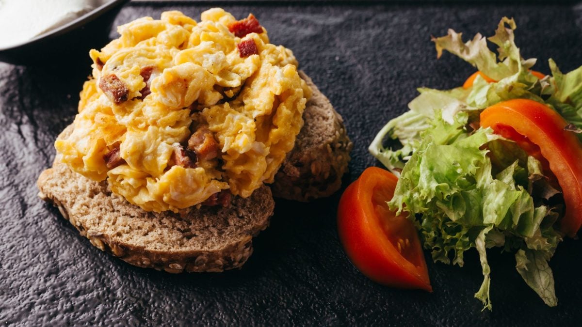 Zwei Scheiben Körnerbrot belegt mit DDR-Kultgericht "Affenfett", daneben frischer Salat mit Tomatenscheiben.