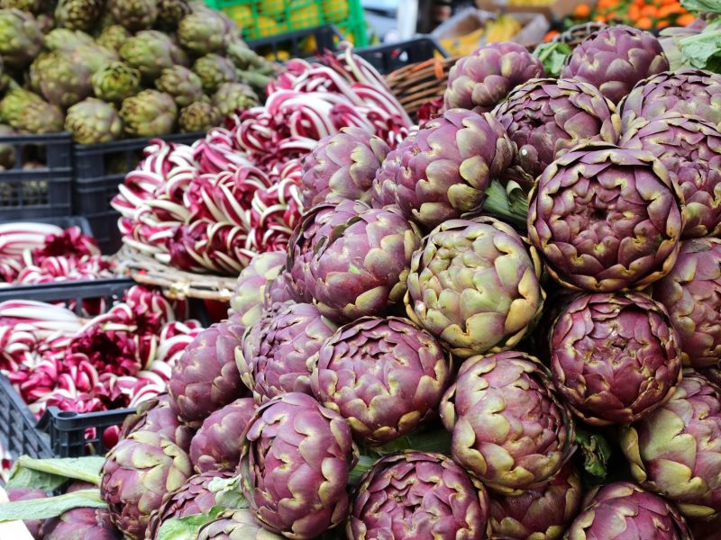 Frontal: Ein Marktstand mit frischen Artischocken und Radicchio.